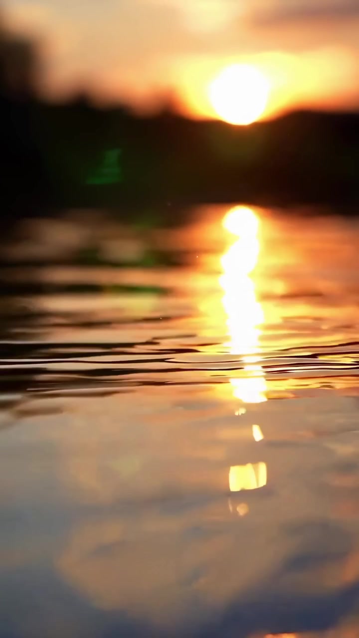 Reflexo dourado do pôr do sol na superfície da água ondulante