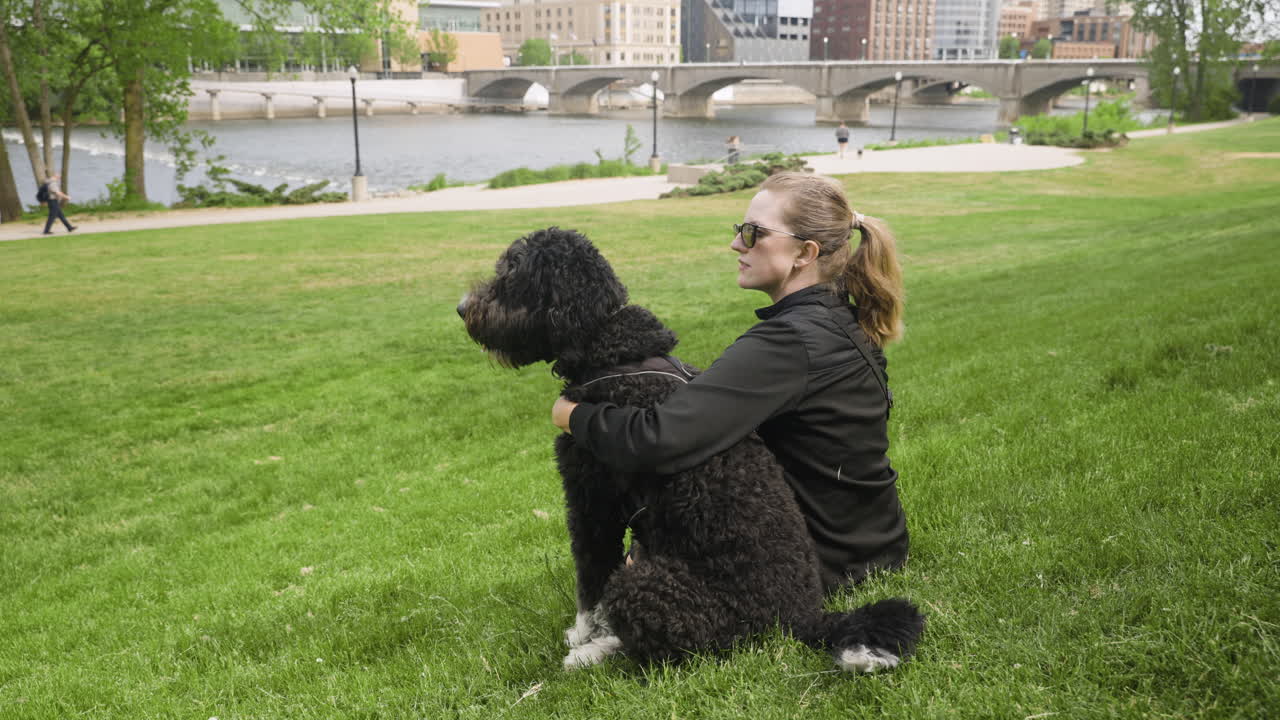 молодая женщина сидит со своей собакой в городском парке.