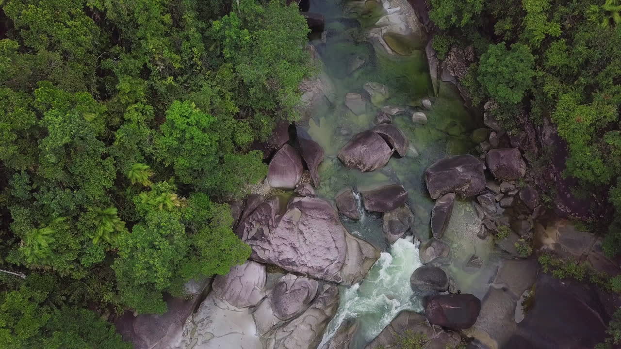a través de una perspectiva aérea en cámara lenta, las rocas de babinda en cairns, australia, revelan rápidos arroyos y densos bosques entrelazados con estructuras de granito, arrojando luz sobre su tranquilidad.