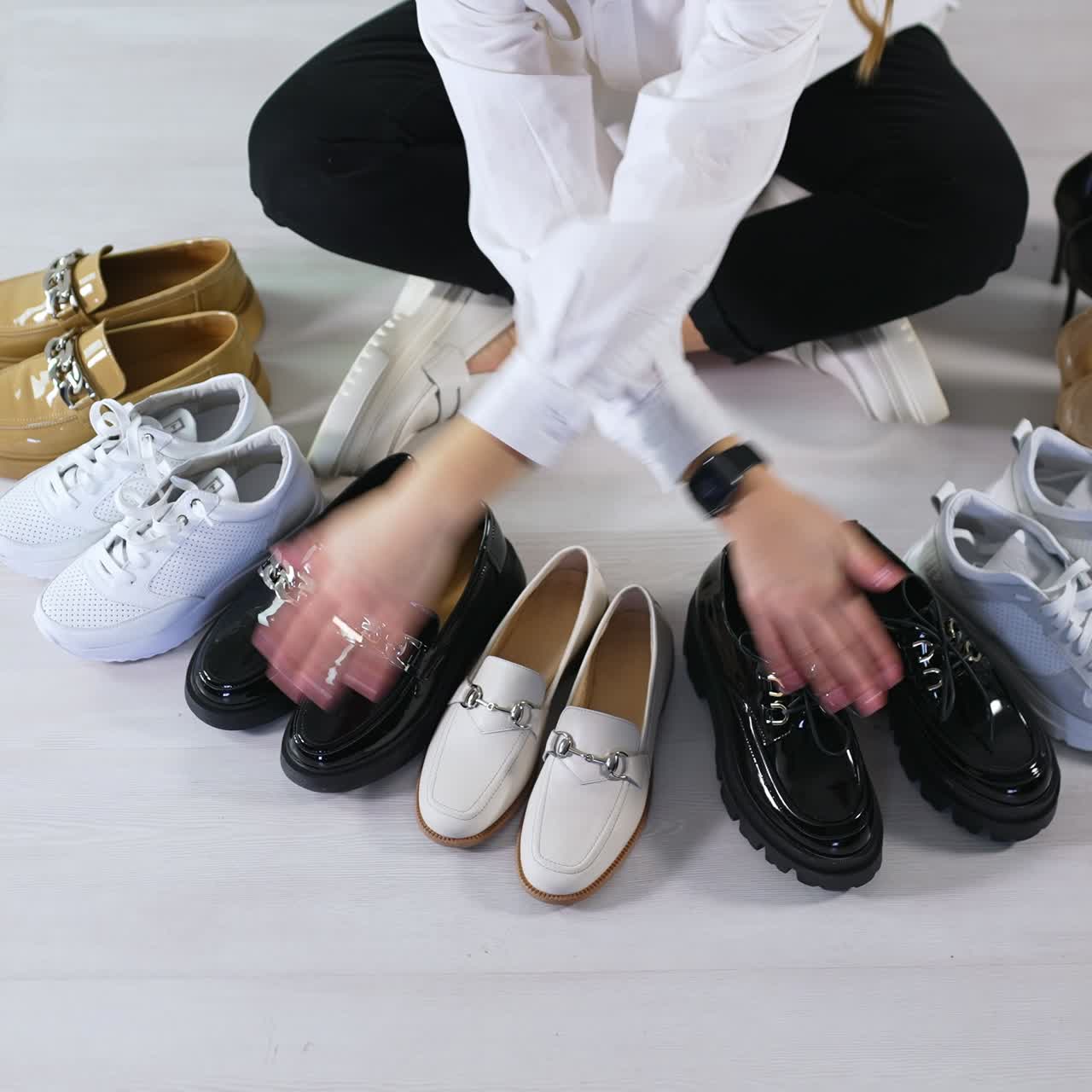 Woman sitting on the floor counts the pairs of shoes in front of her. Variety of footwear presentation. View from top