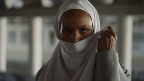 languid black lady hides face with headscarf on embankment