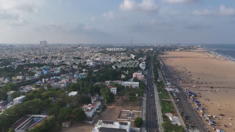 a stunning aerial view of chennai’s iconic marina beach filled with crowd, buildings and metro train construction