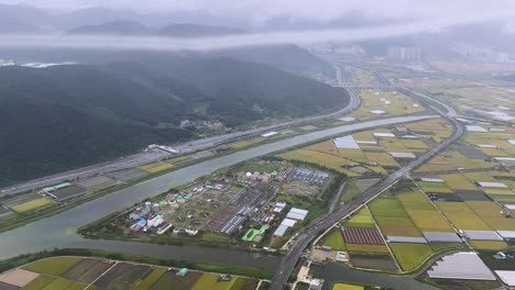foggy aerial view of farmland, a river, and a mountain near busan in a tranquil, misty setting