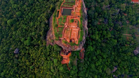 aerial footage showcasing the iconic sigiriya rock fortress rising dramatically above the surrounding jungle in central sri lanka.