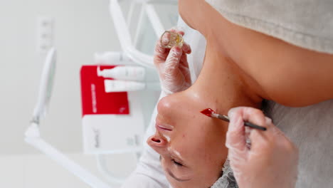 enzyme therapy beautician applying moisturizing medical cream on young woman neck with brush