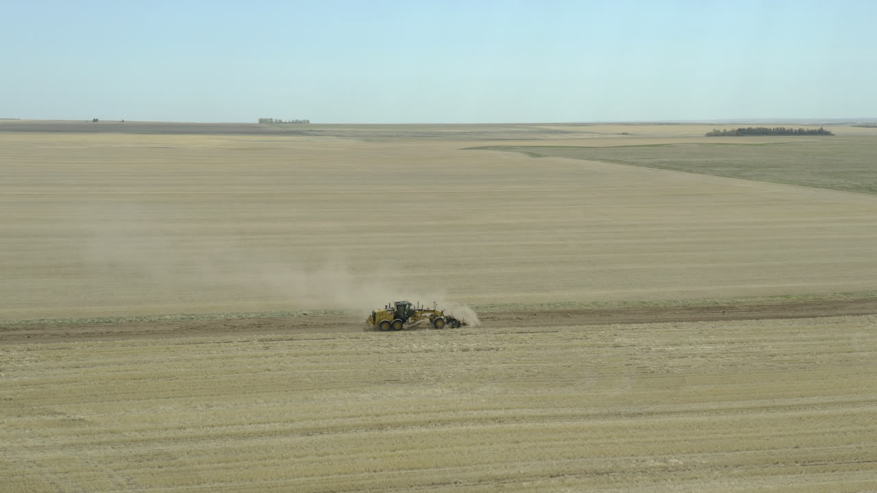 тяжелая строительная техника прокладывает новую дорогу между двумя полями, боковая съемка с воздуха