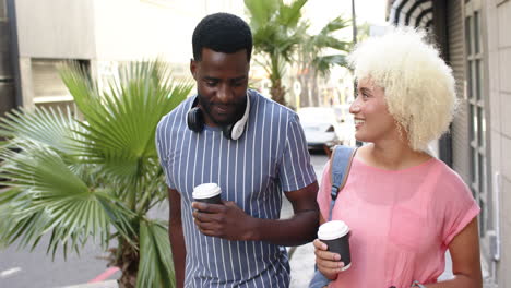 Una-Pareja-Diversa-Disfruta-De-Un-Paseo-Con-Un-Café-En-La-Mano-Durante-Unas-Vacaciones-En-La-Ciudad