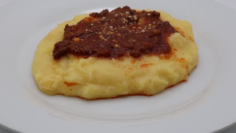 polenta con salsa boloñesa y queso parmesano aislado en blanco