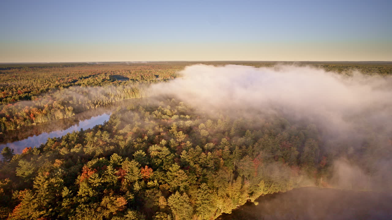Aerial drone pass capturing haze drifting upward from water at daybreak