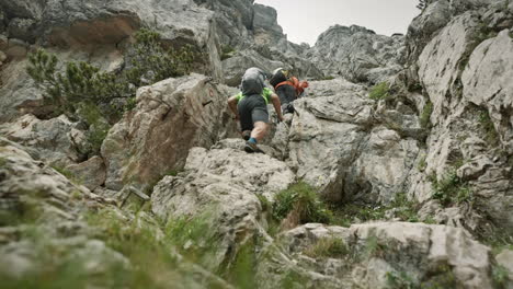 hikers with backpacks climbing up a climb in cloudy conditions