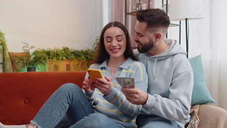 pareja de familia feliz sonriente hombre mujer contando dinero en efectivo uso de teléfono inteligente, ingresos, ahorros, ganar la lotería