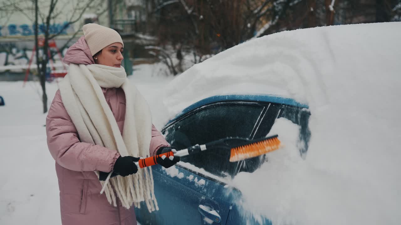 mujer quitando la nieve del coche