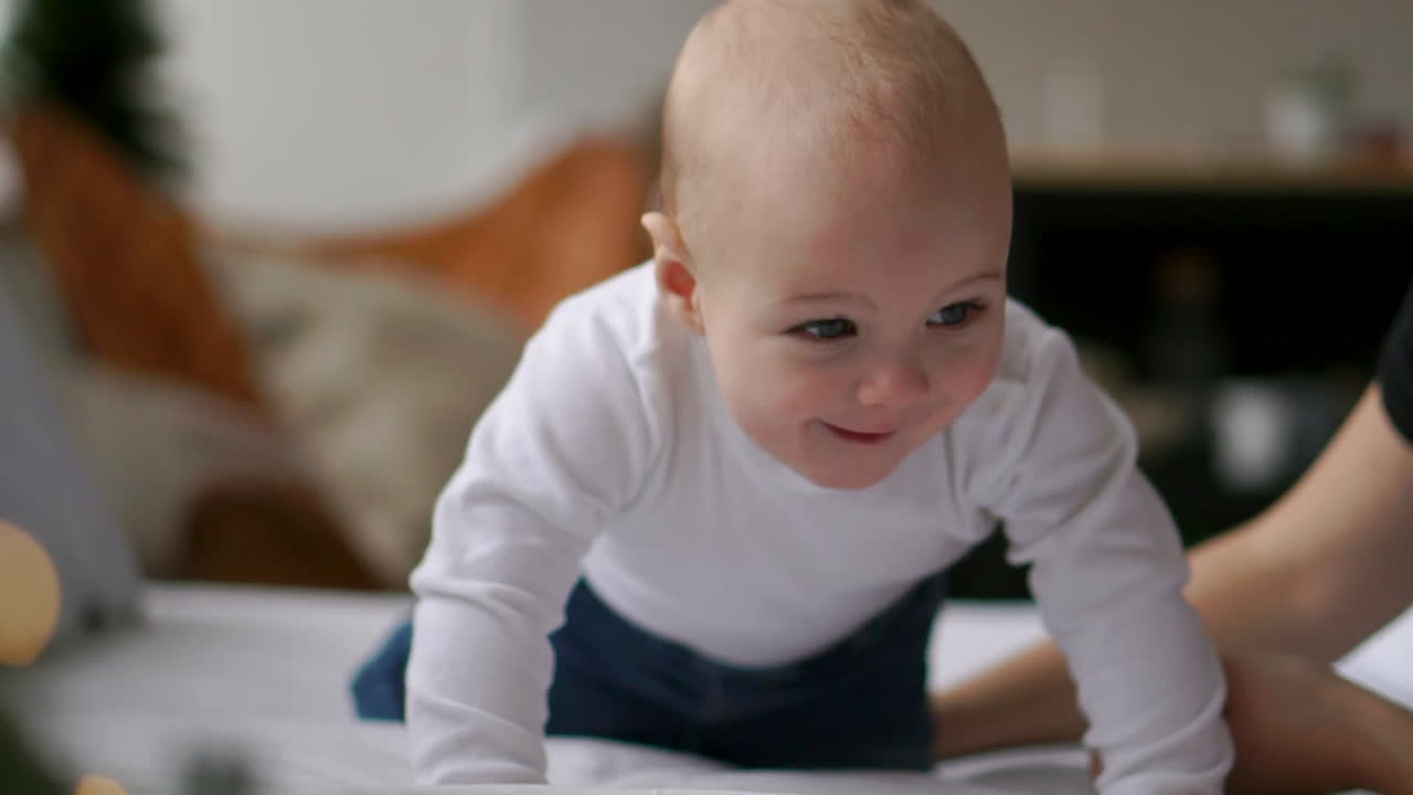 Young mother hugging her newborn child. Mom nursing baby. Woman and new born boy relax in a white bedroom. Family at home. Love, trust and tenderness concept. Bedding and textile for nursery.