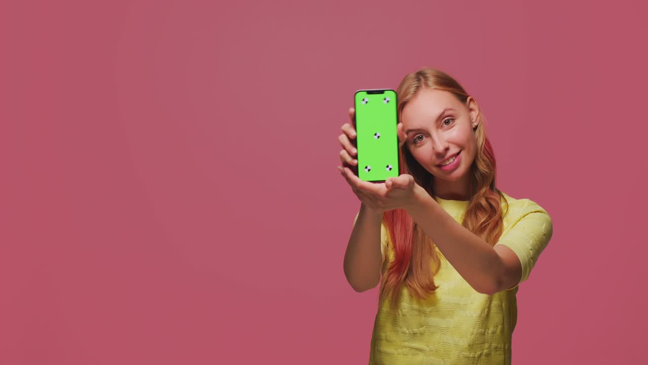 chica joven y bonita mostrando teléfono con pantalla verde plantilla de clave de croma recomienda aplicación. copyspace para anunciar