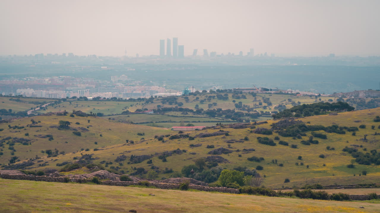 horizonte de madrid desde lejos en un movimiento de sombra de nube de mañana soleada con campos de primavera verdes y amarillos como primer plano