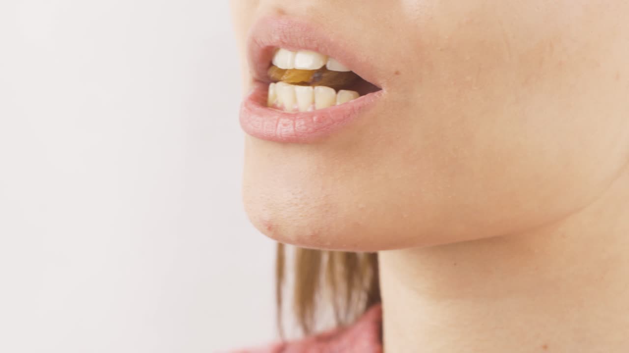 Primo piano di donna che mangia uvetta. Frutta secca.
