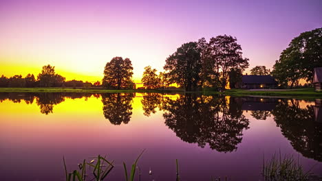 Timelapse-De-Una-Colorida-Puesta-De-Sol-Sobre-Una-Casa-En-Un-Tranquilo-Lago-Reflectante