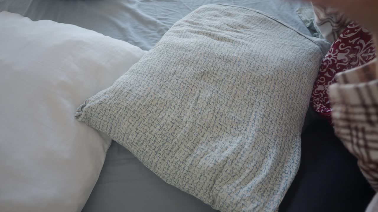 Woman adjusting a pillow on her bed