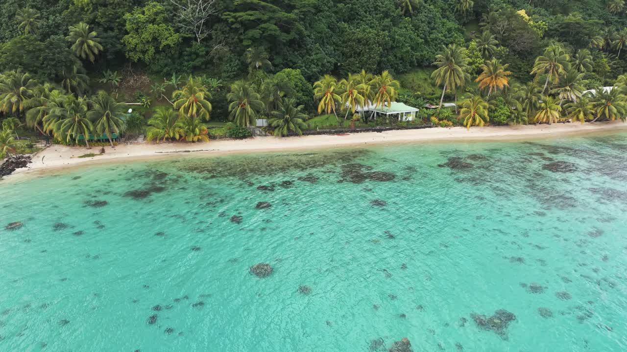 Drone Shot of Beach on Island in French Polynesia. Beachfront Homes in Green Tropical Lush and Turquoise Ocean Water