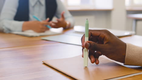 nahaufnahme einer hand eines mannes, der einen stift auf dem tisch hält