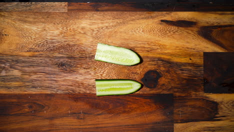 vista superior de una mano masculina cortando la mitad de un pepino en la mitad perpendicular