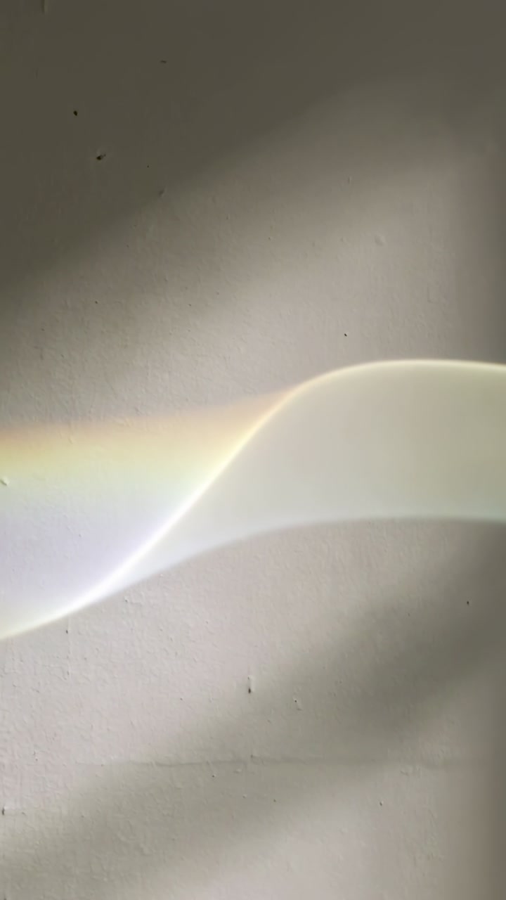 Vertical video: Casting curved band, sunlight entering window sliding across wall, showing specks