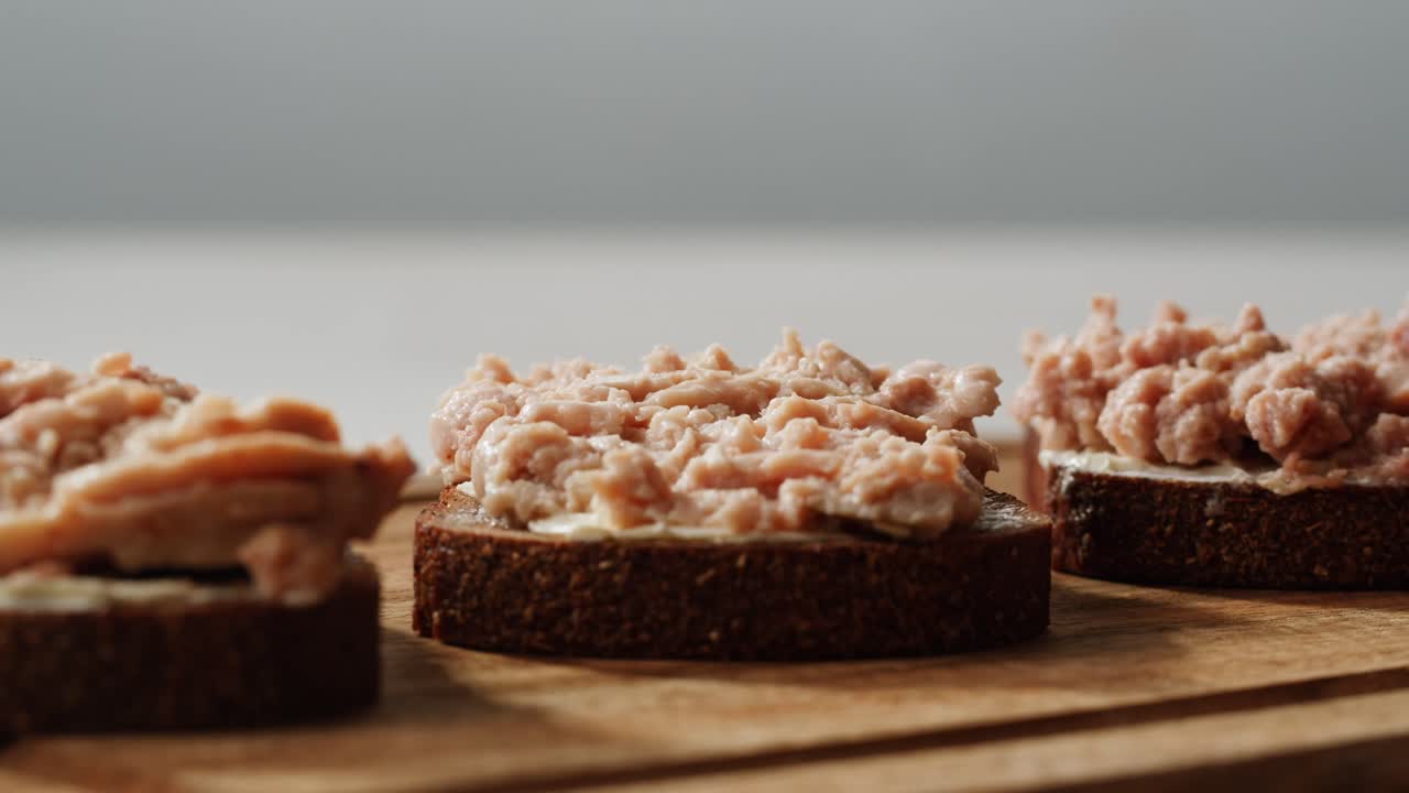 Smoked cod liver in oil in open tin can with fresh greens on wooden table. Seafoods delicacy. High quality 4k footage