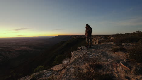 sunset timelapse of friends sitting on a cliff