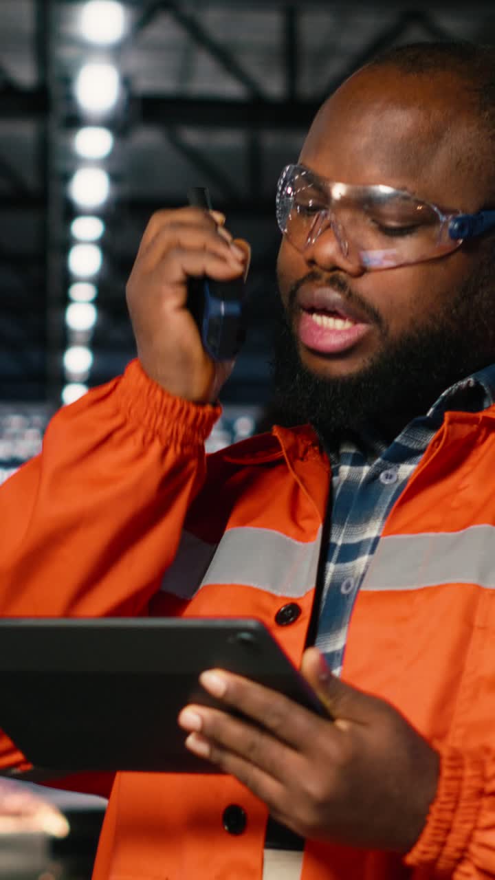 Vertical Video African american professional worker using walkie talkie radio in industry plant
