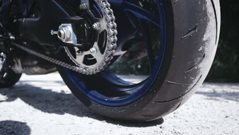 close up shot of the lower part of a motorcycle with focus on the back wheel chain