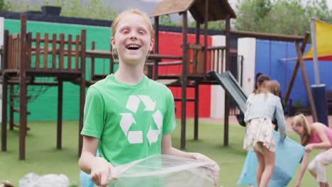 Portrait-of-happy-diverse-schoolchildren-cleaning-with-bags-at-school-playground