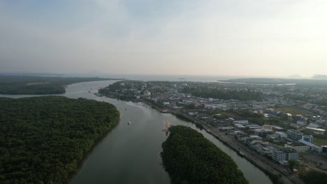 Aerial-drone-panning-up-overlooking-a-canal-of-rivers-surrounded-by-mangrove-forests-in-Krabi-Town-Thailand-during-a-sunset-afternoon