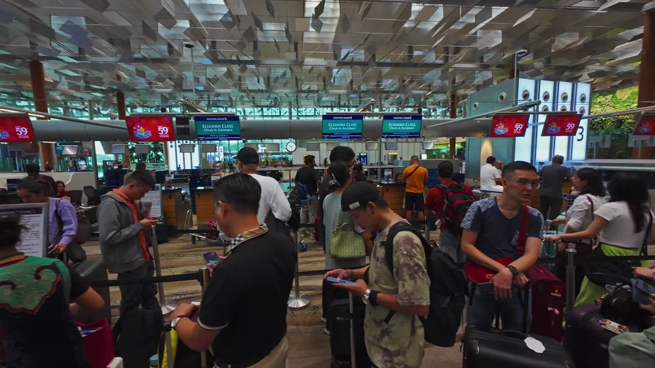 Travelers wait in line at a busy check-in area in Singapore Changi Airport