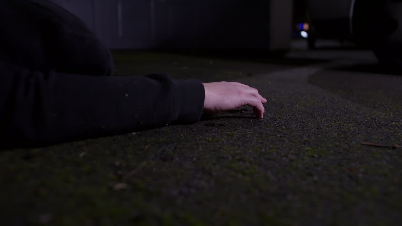 Un uomo sdraiato per terra in un vicolo dopo essere caduto di notte.