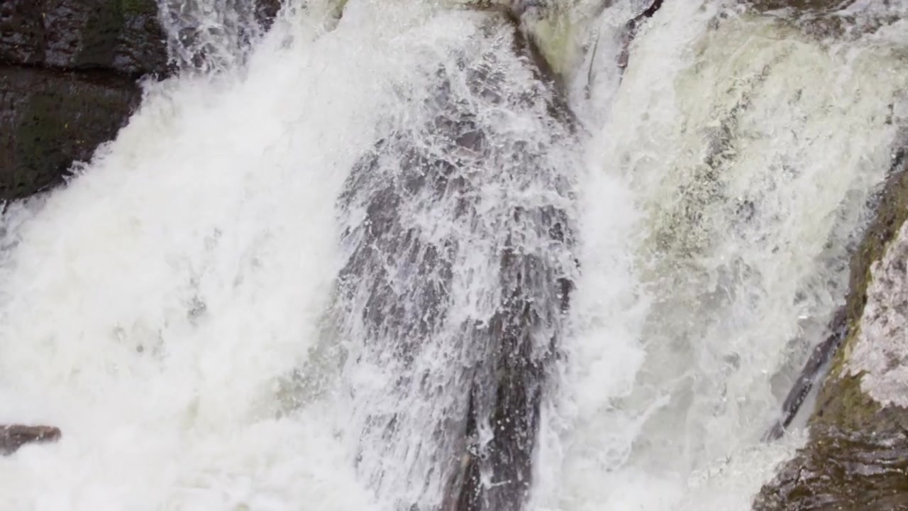 A powerful waterfall crashes over rugged rocks, creating foamy white water in Norway. Ideal for travel content or adventure documentaries.