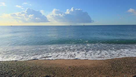 Panoramaaufnahme-Des-Strandes-Mit-Kleinen-Wellen-Und-Booten-Im-Hintergrund