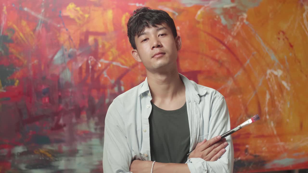 Asian Male Artist Painting And Looking At Abstract Painting