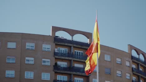 Spanische-Flagge-Vor-Einem-Gebäude,-Das-über-Der-Luft-Fliegt