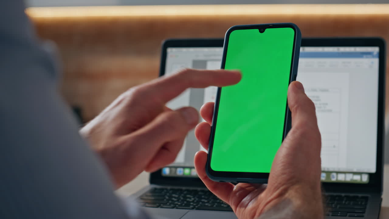 User touching chromakey smartphone at laptop workplace closeup. Man surfing web