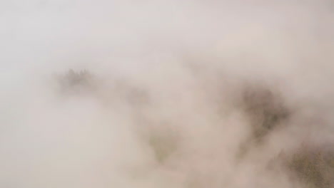 Aerial-of-mist-and-fog-rolling-over-forest-on-mountain