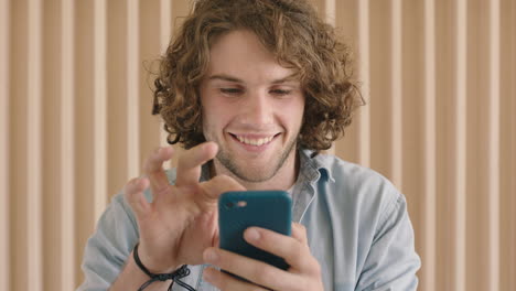 close up portrait of cute friendly young man texting browsing using smartphone mobile technology smiling happy enjoying connection