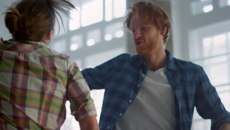 joyful couple enjoying apartment improvement inside. family dancing indoors.