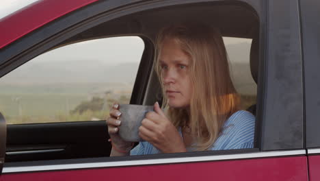 woman on a road trip making a stop to rest with tea and phone