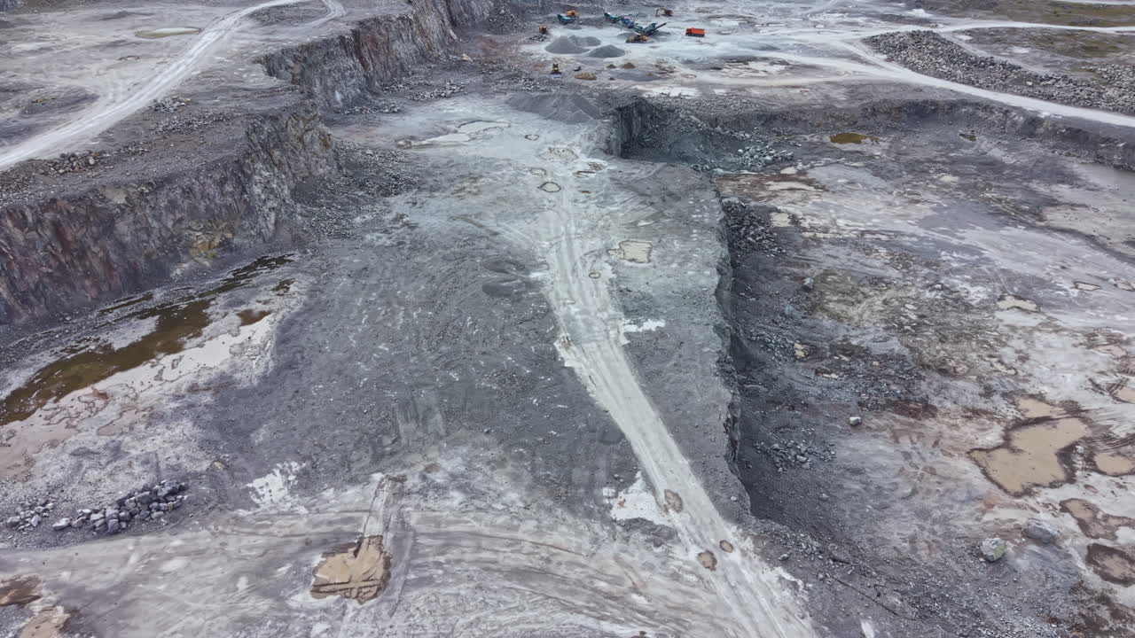 Construction activity taking place at a large quarry site with machinery moving earth during daytime operations