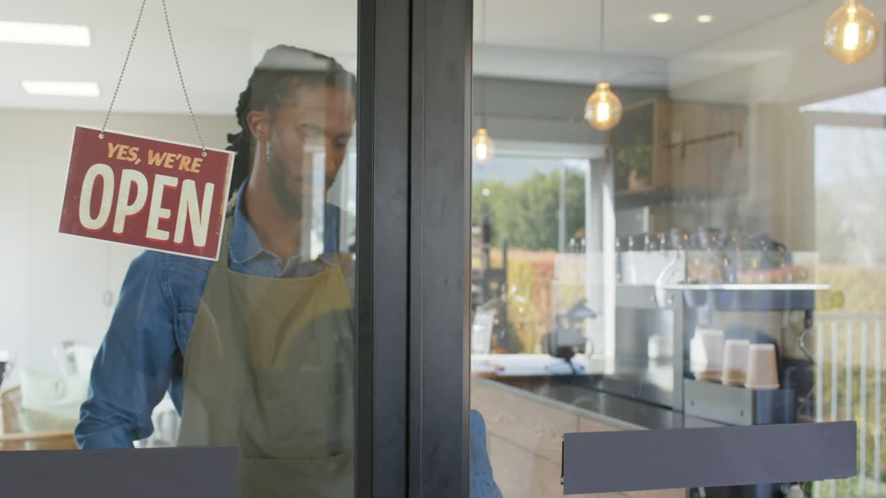 Barista afroamericano che apre una caffetteria, sganciando l'insegna e girandola su