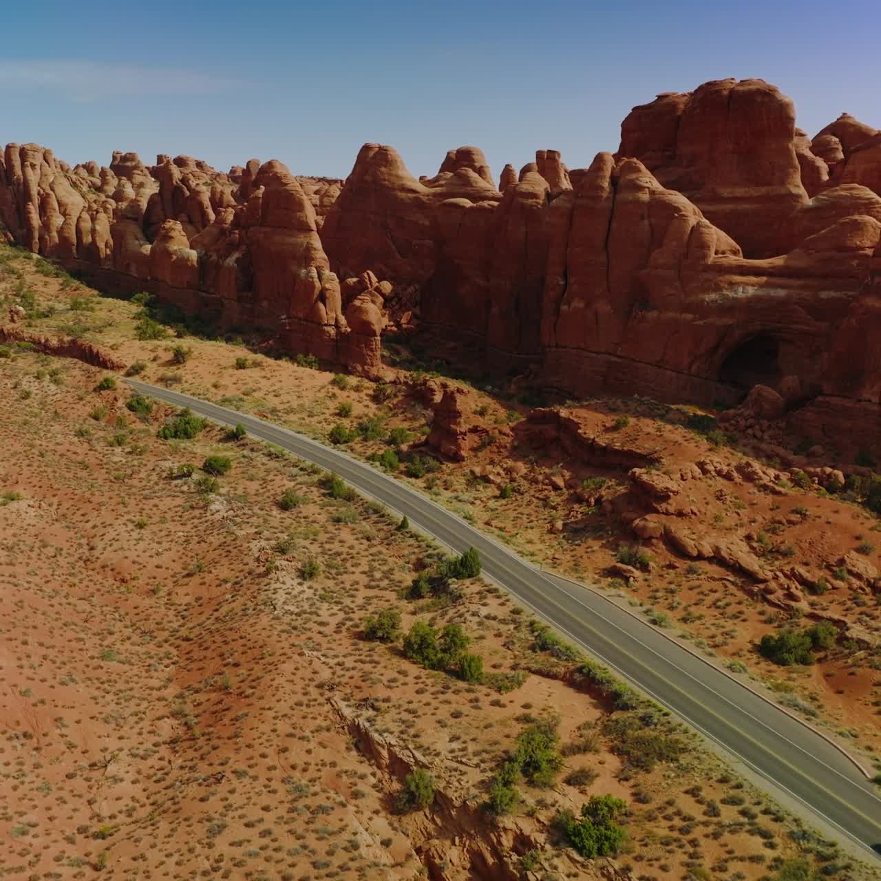 Cars moving by the motorway locating along the odd-shaped orange rocks. Wonderful canyons of Arches national park, Utah, USA