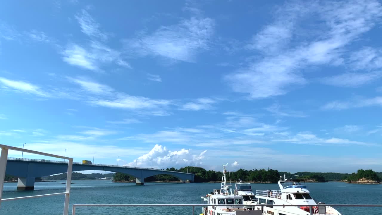 Amakusa Japan timelapse across blue sky to boats in harbour seafront and traffic moving across bridge