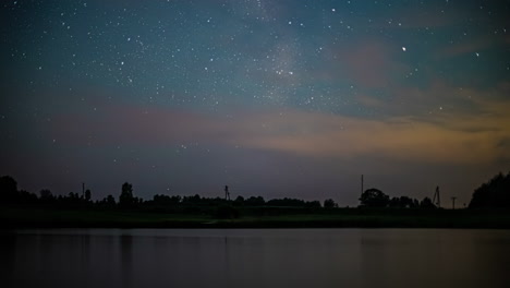 Toma-De-Tiempo-Del-Movimiento-Del-Tráfico-En-La-Carretera-A-Lo-Largo-De-La-Orilla-Del-Lago-En-La-Noche-Sobre-El-Cielo-Nocturno-Estrellado