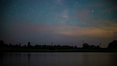 toma de tiempo del movimiento del tráfico en la carretera a lo largo de la orilla del lago en la noche sobre el cielo nocturno estrellado