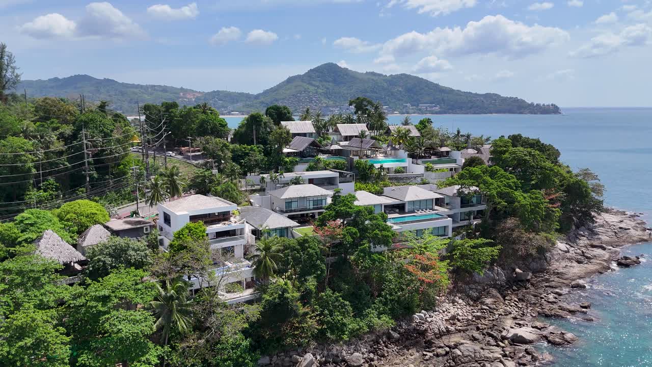 드론 영상은 태국 푸켓의 울창한 초록색과 해안 휴양지, 밝은 낮빛 아래 평화로운 바다 배경으로 포착됩니다.